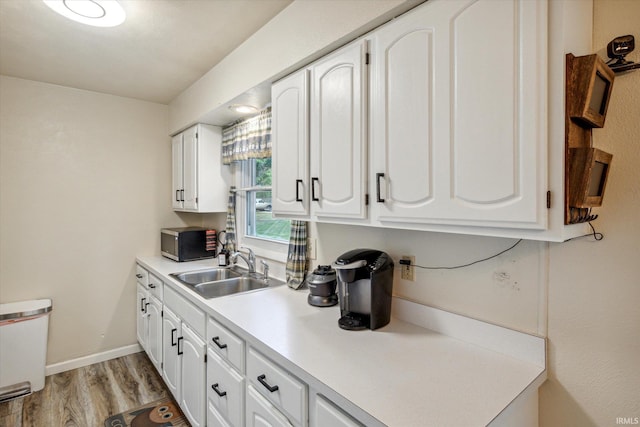 kitchen with white cabinets, light wood-type flooring, and sink