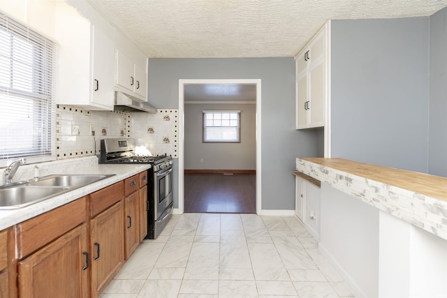 kitchen featuring backsplash, sink, stainless steel range with gas cooktop, white cabinetry, and a textured ceiling