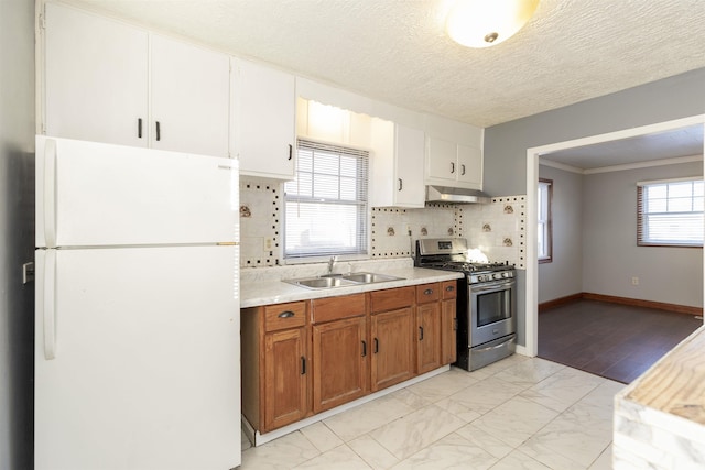 kitchen with tasteful backsplash, gas stove, sink, white cabinets, and white refrigerator