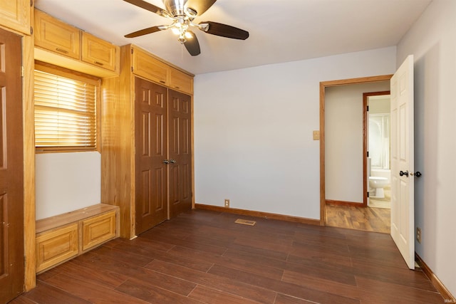 unfurnished bedroom featuring ceiling fan, a closet, dark hardwood / wood-style flooring, and connected bathroom