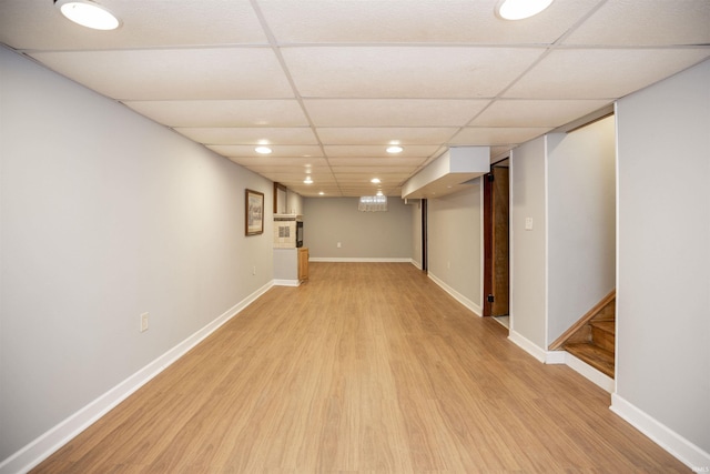 basement with a drop ceiling and light hardwood / wood-style flooring