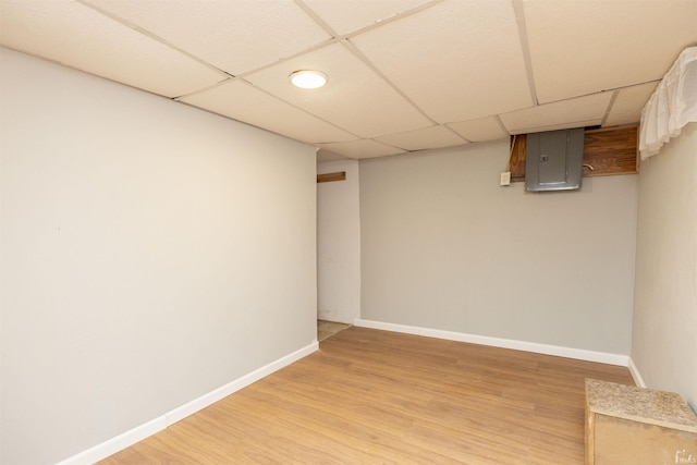 basement with electric panel, light hardwood / wood-style flooring, and a drop ceiling