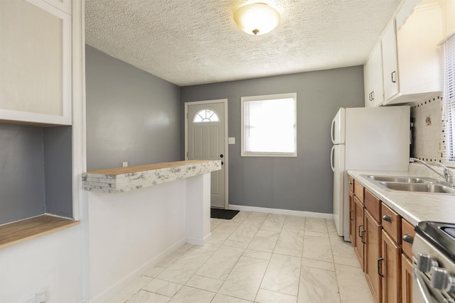 kitchen with electric stove, white fridge, sink, white cabinetry, and a textured ceiling