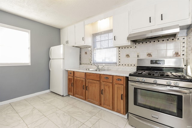 kitchen with white fridge, gas stove, a textured ceiling, wall chimney exhaust hood, and sink