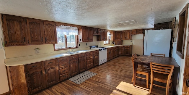 kitchen with light hardwood / wood-style floors, white appliances, dark brown cabinets, a textured ceiling, and sink