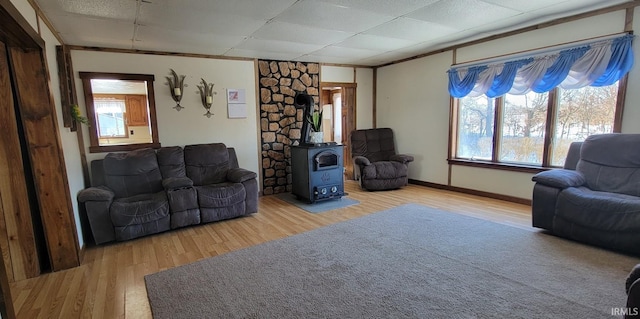 living room featuring hardwood / wood-style flooring, a wood stove, and a drop ceiling