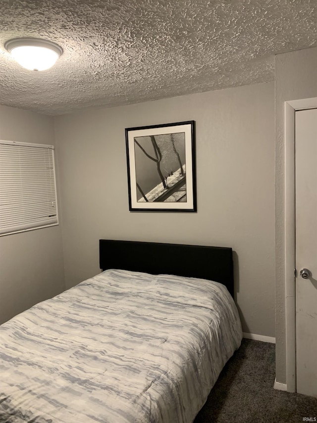 bedroom with dark carpet and a textured ceiling