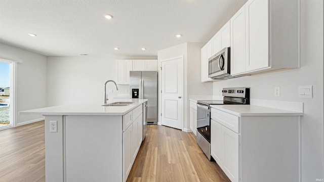 kitchen featuring light hardwood / wood-style floors, a center island with sink, sink, white cabinetry, and appliances with stainless steel finishes