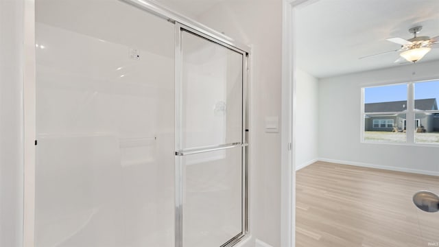 bathroom featuring a shower with shower door, ceiling fan, and hardwood / wood-style flooring