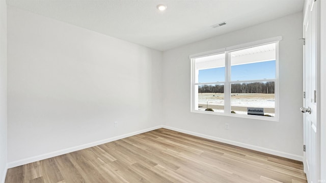 spare room with a textured ceiling and light hardwood / wood-style flooring