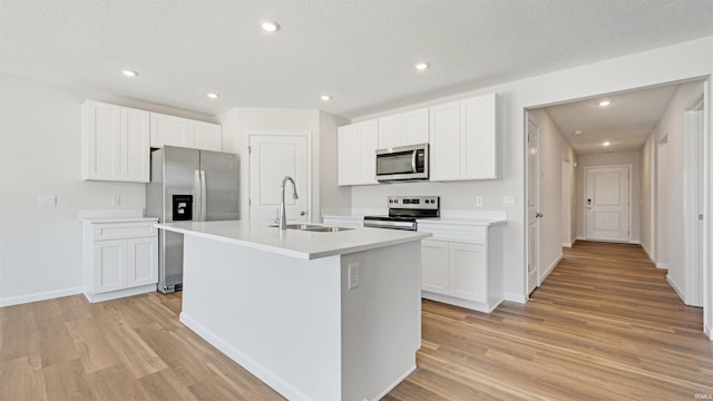 kitchen with a kitchen island with sink, sink, stainless steel appliances, and white cabinetry