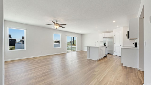 interior space with a textured ceiling, ceiling fan, light hardwood / wood-style flooring, and sink