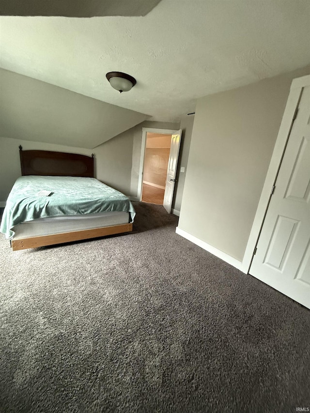 unfurnished bedroom with carpet, a textured ceiling, and vaulted ceiling