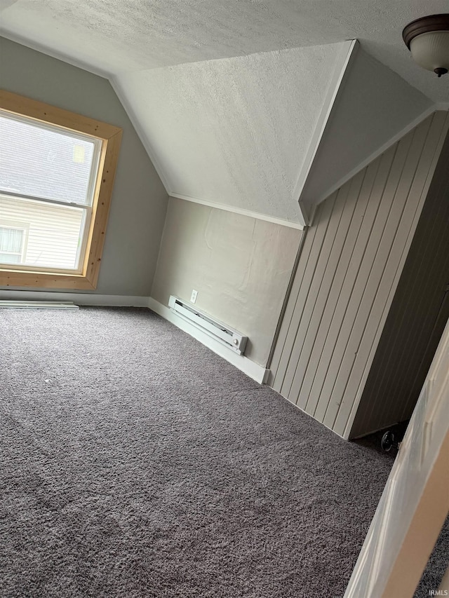 additional living space with a baseboard heating unit, a textured ceiling, vaulted ceiling, and carpet floors