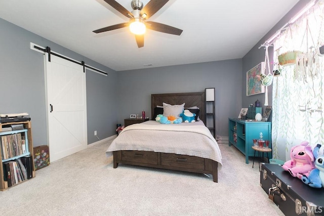 carpeted bedroom featuring ceiling fan and a barn door