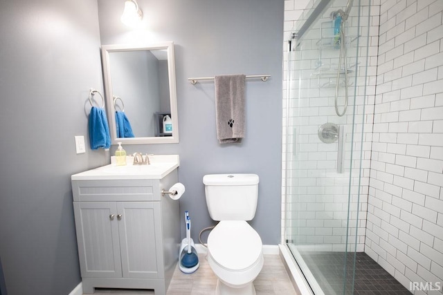 bathroom with toilet, a shower with shower door, and vanity