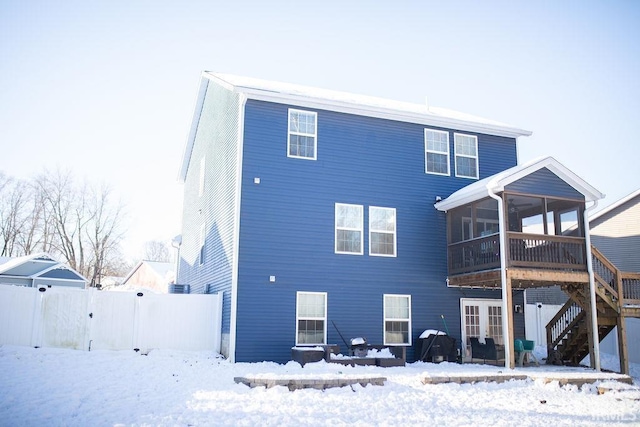 snow covered back of property with a sunroom