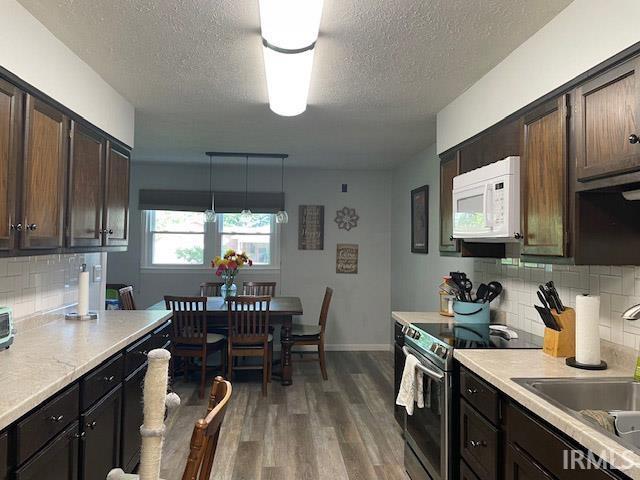 kitchen featuring decorative backsplash, electric stove, decorative light fixtures, and dark brown cabinets