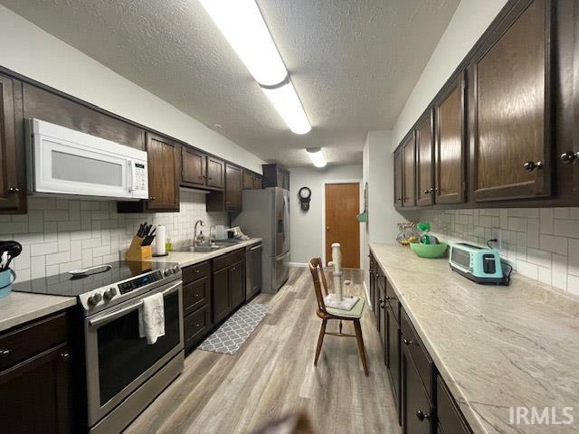 kitchen with decorative backsplash, appliances with stainless steel finishes, sink, and dark brown cabinetry