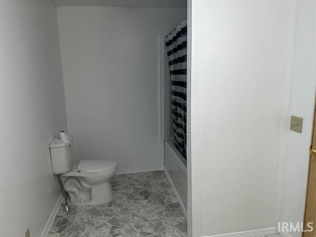 bathroom featuring toilet and shower / tub combo with curtain