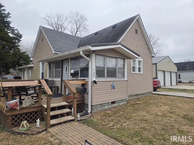 view of side of home with a garage, a wooden deck, a sunroom, and a lawn