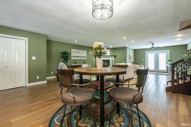 dining room with ceiling fan, hardwood / wood-style floors, a textured ceiling, and french doors