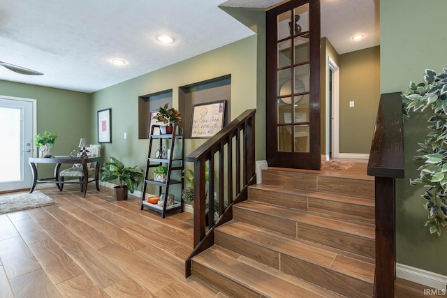 stairs with a textured ceiling and hardwood / wood-style floors