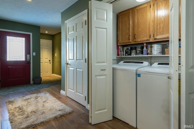 clothes washing area featuring hardwood / wood-style flooring, cabinets, a textured ceiling, and separate washer and dryer