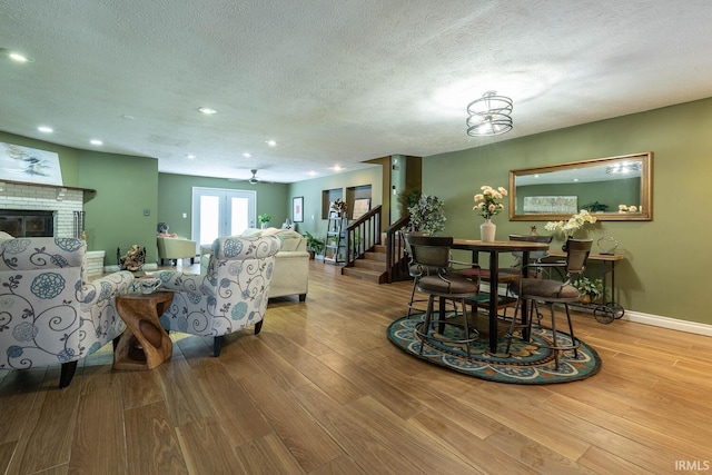 living room featuring light wood-type flooring, ceiling fan, and a textured ceiling