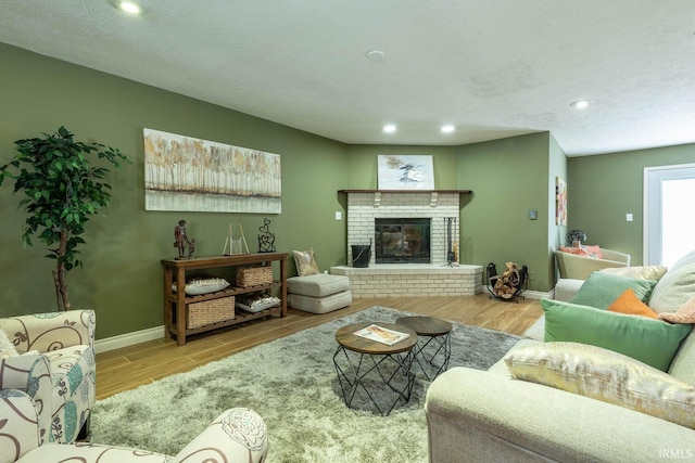 living room featuring a brick fireplace, a textured ceiling, and light hardwood / wood-style flooring