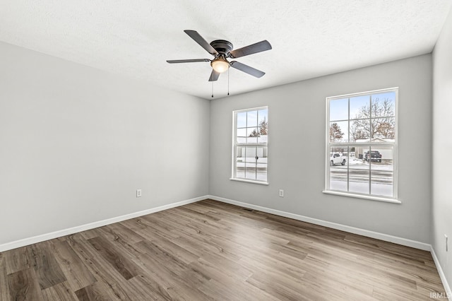 unfurnished room with ceiling fan, light wood-type flooring, and a textured ceiling