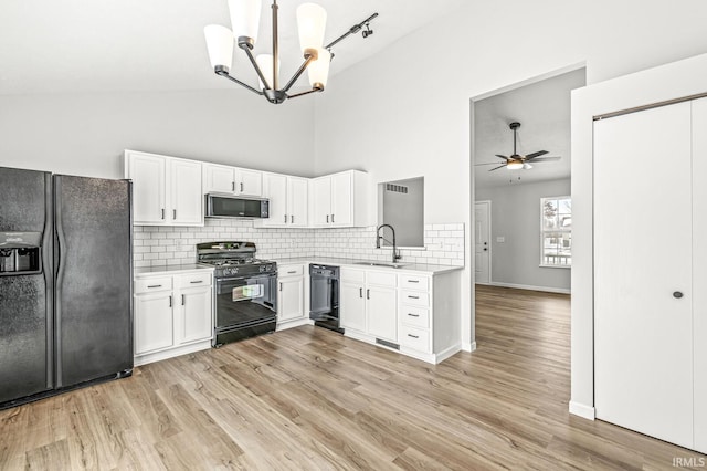 kitchen with ceiling fan with notable chandelier, sink, white cabinets, and black appliances