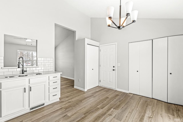 interior space featuring high vaulted ceiling, sink, ceiling fan with notable chandelier, and light hardwood / wood-style flooring