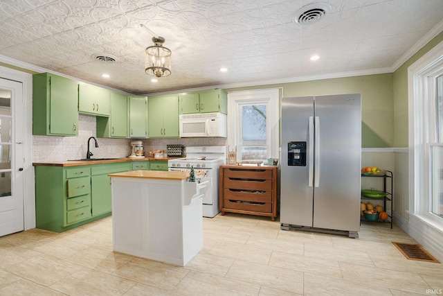 kitchen featuring sink, white appliances, a center island, and green cabinets