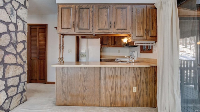 kitchen with light colored carpet, white refrigerator with ice dispenser, and kitchen peninsula