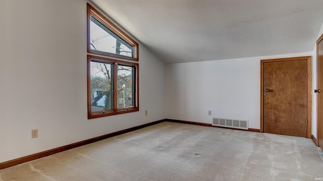 bonus room with light colored carpet and lofted ceiling