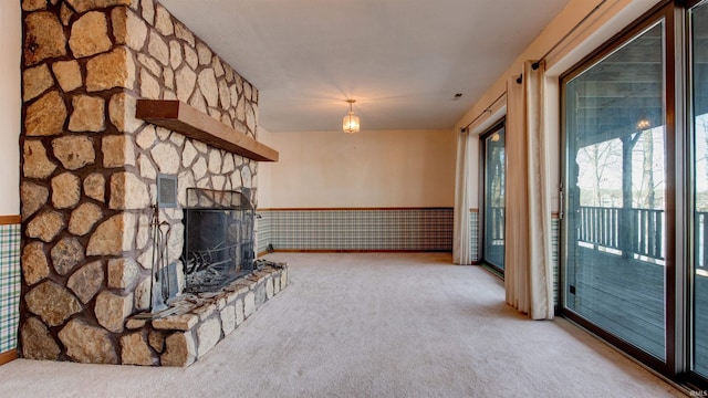 unfurnished living room with light colored carpet and a stone fireplace