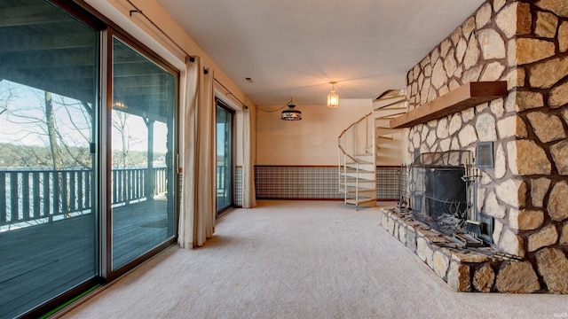 unfurnished living room featuring carpet and a stone fireplace