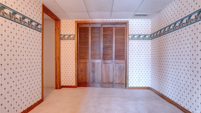 hall with a paneled ceiling and carpet