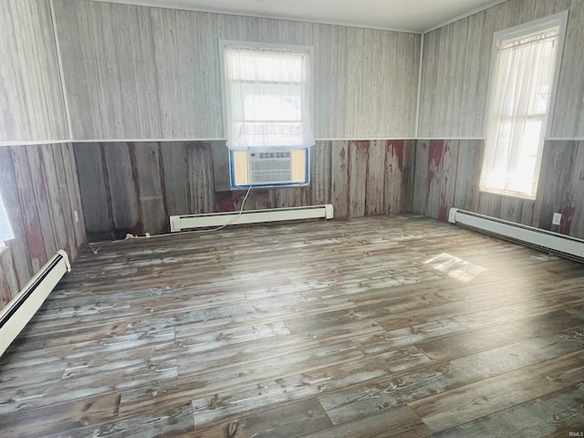 spare room featuring baseboard heating and dark hardwood / wood-style flooring