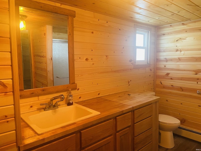 bathroom featuring toilet, vanity, a baseboard heating unit, wood walls, and wood-type flooring