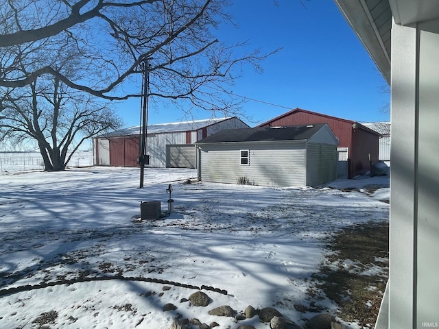 snow covered back of property featuring an outdoor structure