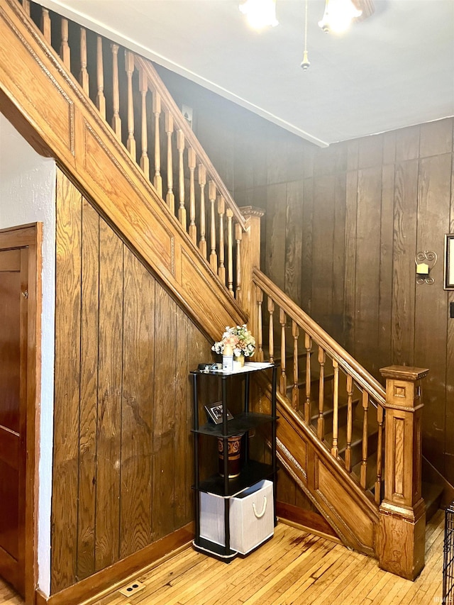 staircase with wooden walls and hardwood / wood-style flooring