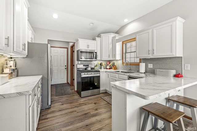 kitchen featuring white cabinetry, appliances with stainless steel finishes, a kitchen bar, and kitchen peninsula