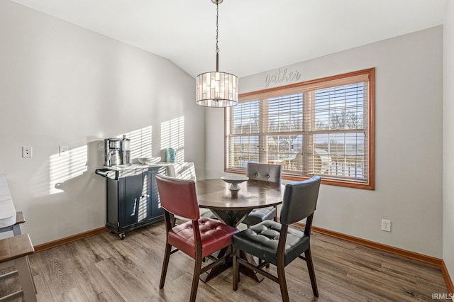 dining room with wood-type flooring, lofted ceiling, and a notable chandelier