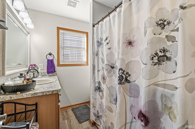 bathroom featuring hardwood / wood-style floors, walk in shower, and vanity