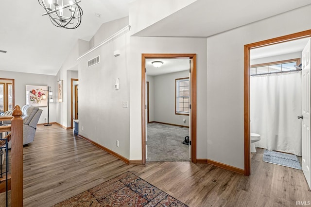 hallway featuring hardwood / wood-style floors, an inviting chandelier, and vaulted ceiling