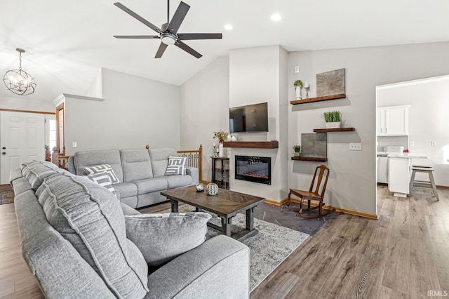 living room with lofted ceiling, light wood-type flooring, and ceiling fan with notable chandelier