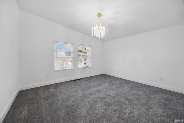 spare room with a chandelier, lofted ceiling, and dark carpet