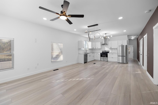 unfurnished living room with ceiling fan, light hardwood / wood-style flooring, and sink